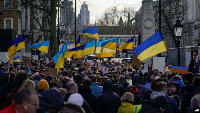 People hold placards and Ukrainian flags as they attend a demonstration in support of Ukraine, outside Downing Street, in London, Feb. 24, 2022.