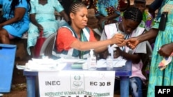 FILE - An electoral official accredits a woman to vote at a polling station during the Anambra State governorship election at Uga, Aguata district in southeast Nigeria, Nov. 6, 2021.