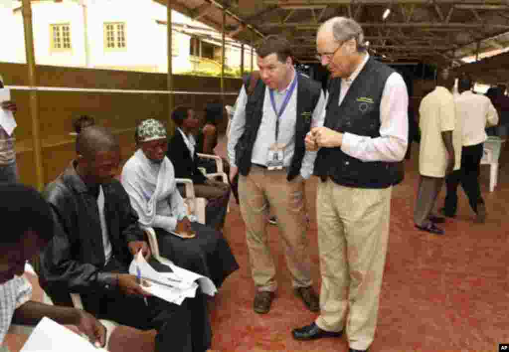 The chief observer for the 2011 European Union mission in Uganda, Edward Scicluna, center right, and an unidentified aide talk to observers as they visit a polling station in the capital Kampala, Friday, Feb 18, 2011. Ugandans are voting in presidential a