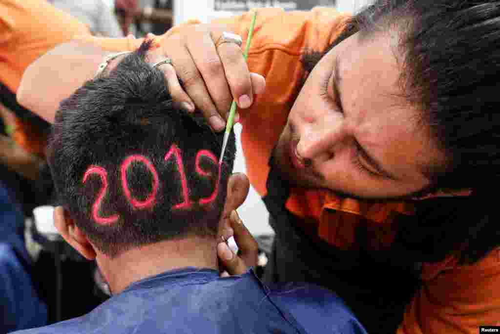 A man applies color to a haircut with&nbsp; &quot;2019&quot;, to welcome the new year at a barbershop in Ahmedabad, India.