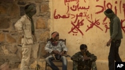 FILE - In this Friday, July 26, 2013 file photo, rebels from the National Movement for the Liberation of the Azawad (NMLA) stand guard outside the former governor's office, in Kidal, Mali. 