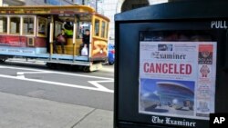 A newspaper headline announcing the closure of large events is displayed as a cable car goes down California Street on March 13, 2020, in San Francisco. (AP Photo/Eric Risberg)