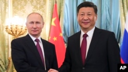 Russian President Vladimir Putin, left, shakes hands with the Chinese President Xi Jinping during a meeting in the Kremlin, in Moscow, Russia, July 4, 2017. 