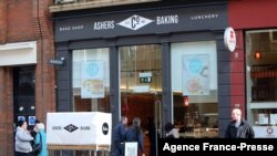 FILE - Pedestrians and customers walk by a branch of Ashers Baking Company, the bakery that refused to make a cake depicting a pro-gay marriage slogan ordered by gay rights activist Gareth Lee, in Belfast on March 26, 2015.