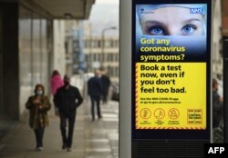 People walk past a display featuring health advice in the shopping district in central Sheffield, south Yorkshire, Oct. 21, 2020. (AFP)