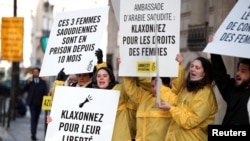 FILE - Demonstrators from Amnesty International hold placards outside the Saudi Arabian Embassy to urge Saudi authorities to release jailed women's rights activists Loujain al-Hathloul, Eman al-Nafjan and Aziza al-Yousef in Paris, France, March 8, 2019. 