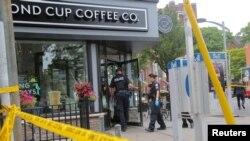 Police officers enter a coffee shop damaged by gunfire while investigating a mass shooting on Danforth Avenue in Toronto, Canada, July 23, 2018. 