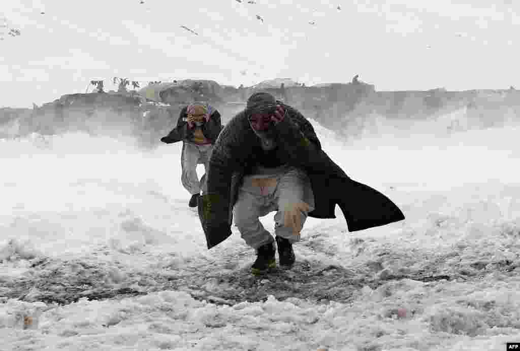 Survivors of an avalanche run to get relief goods distributed by an Afghan army helicopter in the Paryan district of Panjshir province, north of Kabul.