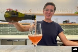 Erin Coburn, owner of the minimo wine shop in Oakland, Calif., pours a natural wine at her tasting bar on Sept. 7, 2023. (AP Photo/Haven Daley)