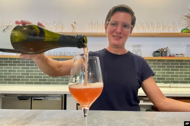 Erin Coburn, owner of the minimo wine shop in Oakland, Calif., pours a natural wine at her tasting bar on Sept. 7, 2023. (AP Photo/Haven Daley)