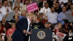 Presiden AS Donald Trump bersalaman dengan pendukungnya, Gene Huber, dalam sebuah kampanye di Melbourne, Florida (17/2). (AP/Chris O'Meara)