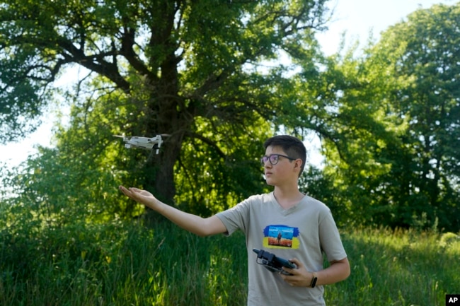 Andriy Pokrasa, 15, lands his drone on his hand during an interview with The Associated Press in Kyiv, Ukraine, Saturday, June 11, 2022. Andriy is being hailed in Ukraine for stealthy aerial reconnaissance work he has done with his dad in the ongoing war with Russia. They used their drone to help the country's military spot, locate and destroy Russian targets in the early days of the Russian invasion. (AP Photo/Natacha Pisarenko)