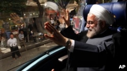 Iranian presidential candidate Hasan Rowhani, a former Iranian nuclear negotiator, waves, from his bus, during his campaign tour to the western city of Sanandaj, Iran, June 10, 2013.