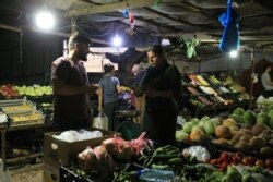 A displaced Iraqi woman from the minority Yazidi sect, who fled the Iraqi town of Sinjar, buys vegetables at the Khanki camp on the outskirts of Dohuk province, July 31, 2019.