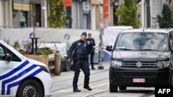 A police officer gestures as he stands guard in front of the house in the Schaerbeek area of Brussels on Octo. 17, 2023, where the suspected perpetrator of the attack in Brussels was shot dead during a police intervention.