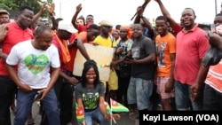 Manifestants posant avec une pancarte sur laquelle est écrit "retour à la constitution de 92, vote de la diaspora, 50 ans ça suffit!", à Lomé, le 6 septembre 2017. (VOA/Kayi Lawson)