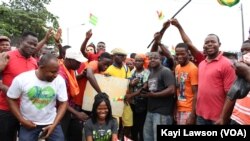 Manifestants posant avec une pancarte sur laquelle est écrit "retour à la constitution de 92, vote de la diaspora, 50 ans ça suffit!", à Lomé, le 6 septembre 2017. (VOA/Kayi Lawson)