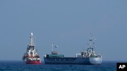 FILE—A cargo ship, right, and a ship belonging to the Open Arms aid group, are loaded with 240 tons of canned food destined for Gaza prepare to set sail outside the Cypriot port of Larnaca, Cyprus, on Saturday, March 30, 2024. 