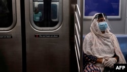 (FILES) In this file photo taken on July 16, 2020, a woman wearing a face mask and shield sits in a subway train during rush hour amid the coronavirus pandemic in New York City. - The US Centers for Disease Control and Prevention have issued a…