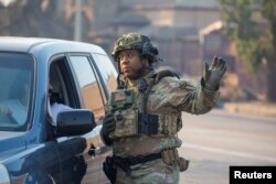 A National Guardsman talks with a driver near damaged structures burned from a wildfire in Altadena, California, on Jan. 10, 2025.