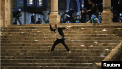 Një palestinez hedh gurë ndaj policisë izraelite gjatë përplasjeve në xhaminë Al-Aqsa