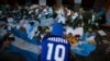 A fan mourns in front of flowers and posters left in tribute to Diego Maradona at the entrance of the Boca Juniors stadium known as La Bombonera in Buenos Aires, Argentina, Nov. 27, 2020. Maradona died Nov. 25 at age 60.