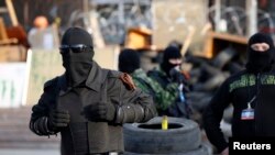 Masked pro-Russia militants stand guard outside a regional government building they seized in Donetsk, eastern Ukraine, April 22, 2014.