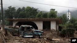 Mexico Tropical Weather: A pickup truck lays destroyed next to a house damaged by a mudslide in Xaltepec, on the mountainous north of Puebla state, Mexico, Sunday, Aug. 7, 2016. 