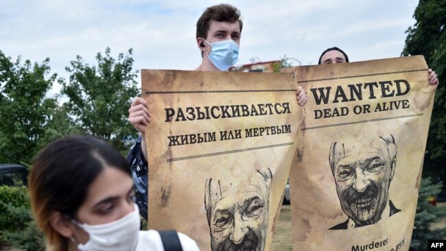 Opposition supporters hold up "Wanted" posters with images of Belarusian President Alexander Lukashenko during protests over the country's disputed presidential election, in Minsk, Aug. 18, 2020.