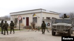 Armed men, believed to be Russian servicemen, stand guard outside a Ukrainian military unit in the village of Perevalnoye outside Simferopol, March 11, 2014.