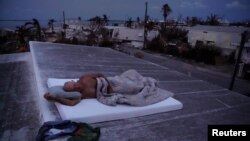 Matt Finn seeks a breeze as he lays down on the roof of his house that is still without power following Hurricane Irma in Big Pine Key, Florida, Sept. 25, 2017.