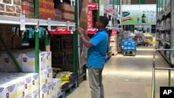 FILE: A man takes images of goods in a shop to share before buying them in Harare, in this Wednesday, Oct, 9, 2019. (AP Photo/Tsvangirayi Mukwazhi)