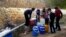 This frame grab from video provided By Yomyat Kzefeh Hawen Fi Dimashq (Diary of a Mortar Shell in Damascus), a Damascus-based media outlet that is consistent with independent AP reporting, shows Syrian residents filling up buckets and gallons of spring water from a pipe on the side of the road, in Damascus.