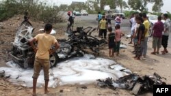 Yemenis inspect a charred vehicle following a suicide car bombing that targeted the convoy of Aden's governor, in the southern city of Aden on July 15, 2016.