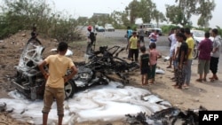 也门人在围观一辆自杀汽车炸弹杀手为刺杀亚丁市长而被炸毁的汽车。（2016年7月15日）