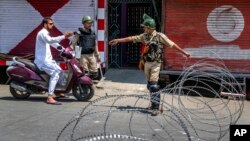 Indian paramilitary soldiers question a person on a scooter before letting him pass at a barbed-wire road checkpoint set up by Indian security forces in Srinagar, Indian-controlled Kashmir, July 7, 2017. Government forces imposed curfew-like restrictions in many parts of Indian-controlled Kashmir to stop anti-Indian protests ahead of the first death anniversary of rebel leader Burhan Wani on Saturday. His killing by security forces last year sparked violent street clashes and almost daily protests throughout the region.