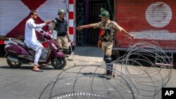 Indian paramilitary soldiers question a person on a scooter before letting him pass at a barbed-wire road checkpoint set up by Indian security forces in Srinagar, Indian-controlled Kashmir, July 7, 2017. 