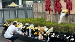 A man offers flowers outside the "Zhuhai People's Fitness Plaza" where a man rammed his car into people exercising at the sports center, in Zhuhai in southern China's Guangdong province on Nov. 13, 2024. 