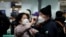 A woman wearing a mask to prevent contracting the coronavirus adjusts her husband's mask as they wait to check in at Incheon International Airport in Incheon, South Korea, March 19, 2020.
