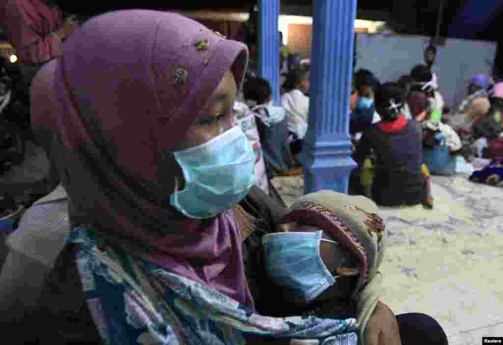 Warga desa yang mengungsi dari desanya di lereng Gunung Kelud, menggendong anaknya di tempat penampungan sementara di desa Sumber Agung, Kediri, Jawa Timur (14/2). (Reuters/Sigit Pamungkas)