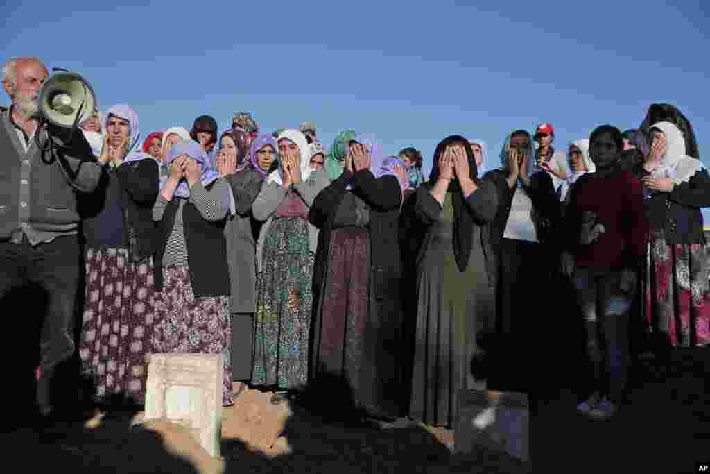 Kurdish mourners pray during the funeral of Kurdish fighters Hanim Dabaan, 20, Idris Ahmad, 30, and Mohammed Mustafa, 25, at a cemetery in Suruc, Turkey, Oct. 21, 2014. 