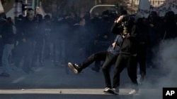 Protester kicks tear-gas canister toward riot police during minor clashes at a protest of the 24-hour strike in Athens, Feb. 20, 2013.