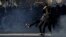 Protester kicks tear-gas canister toward riot police during minor clashes at a protest of the 24-hour strike in Athens, Feb. 20, 2013.