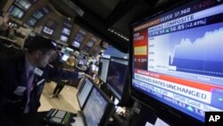 A television screen at the post of specialist Stephen Ruiz, left, displays the decision of the Federal Reserve, on the floor of the New York Stock Exchange Tuesday, Aug. 9, 2011.