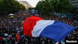 Seorang warga mengibarkan bendera Prancis di saat kerumunan warga berkumpul di Place de la Republique di Paris, menyusul pengumuman hasil pemilu parlemen Prancis pada 7 Juli 2024. (Foto: Reuters/Abdul Saboor)