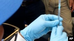 FILE - A health worker prepares an Ebola vaccine to administer to health workers during a vaccination campaign in Mbandaka, Democratic Republic of Congo, May 21, 2018. 