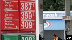 Prices are shown as Jaqueline Henderson pumps gas at a station in Portland, Ore., Friday, July 29, 2011