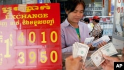 FILE - A currency trader counts Cambodian riels to exchange for U.S. dollars at a money exchange stall in the capital Phnom Penh, Cambodia, Feb. 15, 2008. Cambodia racked up $278 million in U.S. loans under the Lon Nol government in the 1970s.