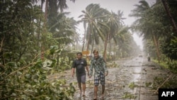 Residents brave rains and strong wind as they walk past uprooted trees along a highway in Can-avid town, Eastern Samar province, central Philippines, May 14, 2020, as Typhoon Vongfong makes landfall.