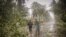 Residents brave rains and strong wind as they walk past uprooted trees along a highway in Can-avid town, Eastern Samar province, central Philippines, May 14, 2020, as Typhoon Vongfong makes landfall.